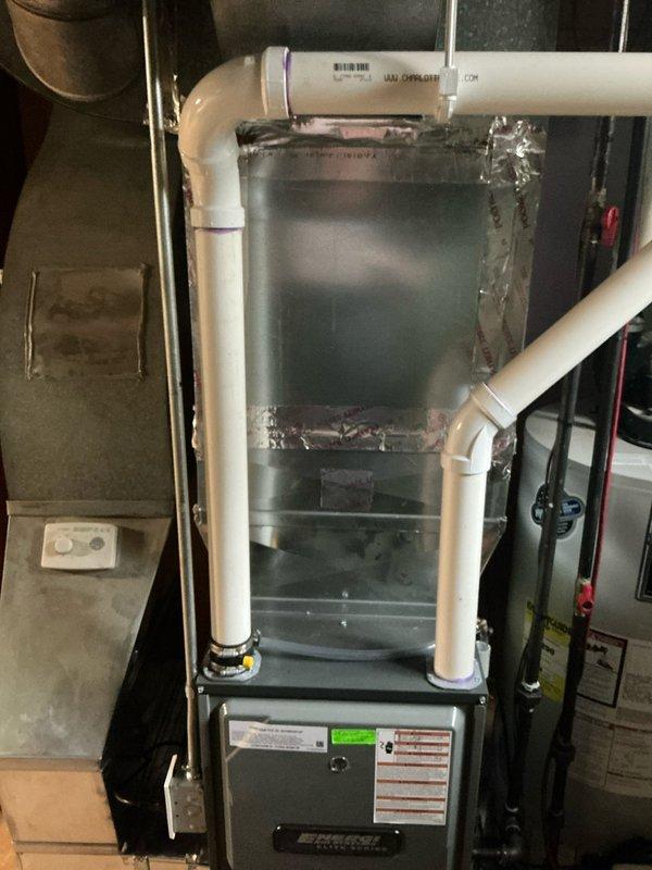 Completed annual AC tune-up and maintenance on a 30-year-old Lennox system located in basement utility area. Performed comprehensive inspection of furnace unit, verified proper operation of all components, checked venting system with white PVC intake and exhaust pipes, and documented equipment condition with photos showing furnace, ductwork, and surrounding mechanical systems in satisfactory working order.