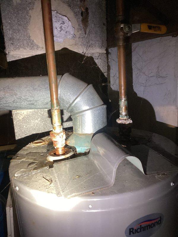 Responded to no hot water call for 5-year-old Richmond water heater. Upon inspection, discovered severe corrosion and rust at copper pipe connections on top of unit, indicating failed tank integrity with water leakage at inlet/outlet ports. Documented extensive deterioration around pipe penetrations with photographic evidence showing orange-brown discoloration consistent with ongoing water seepage. Unit deemed non-repairable due to tank failure and recommended immediate replacement to restore domestic hot water service.