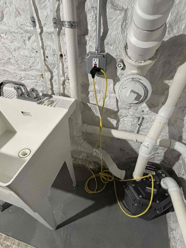 # Laundry Room Plumbing Rework

Completed comprehensive plumbing system rework in basement utility area. Reconfigured white PVC drainage piping with new vertical and horizontal runs, installed black coupling connectors, and secured all lines with proper metal clamps at appropriate intervals. Performed diagnostic testing of water heater/boiler unit and verified all connections for proper drainage flow and system integrity.