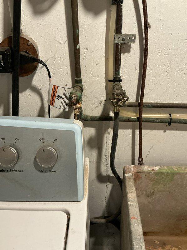 Conducted comprehensive plumbing assessment of 90-year-old residential property with aging copper pipe infrastructure showing significant corrosion and patina buildup. Documented existing conditions of utility area plumbing system, including corroded gate valves, deteriorating copper supply lines, and outdated pipe mounting hardware requiring replacement. Photographed under-sink plumbing configurations and laundry area utility connections to provide detailed estimate for complete pipe replacement project.