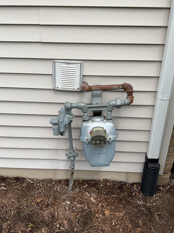 Responded to request for water heater replacement estimate on a nine-year-old unit. Conducted on-site inspection and documented existing water heater installation located in utility room adjacent to laundry equipment. Assessed current system configuration, gas supply connections, venting arrangement, and surrounding plumbing infrastructure. Photographed interior installation area showing utility room layout and exterior gas meter assembly with associated piping network. Provided customer with replacement options and pricing for new water heater installation.