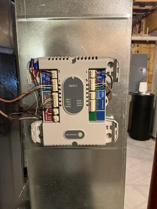 Responded to no heat call following recent furnace installation. Upon arrival, found existing HZ311 zoning control panel was not communicating with newly installed equipment. Verified all zone damper wiring connections at control board terminals and confirmed proper 24V power supply to panel. Traced thermostat wiring from zones to controller and verified continuity on all circuits. Checked damper actuators for proper operation and confirmed zone indicators were functioning on control panel display. Reprogrammed zoning controller to interface with new furnace control board and cycled system through all three zones to verify proper call for heat and damper positioning. System restored to full operation with all zones calling for and receiving heat as designed.