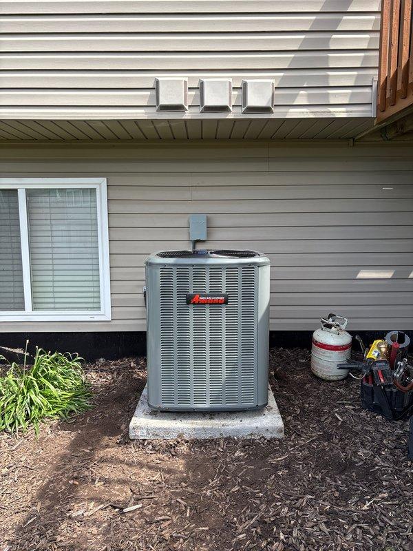 Completed full air conditioning system replacement at residential property. Installed new Amana outdoor condensing unit on concrete pad with proper electrical connections and conduit routing, established refrigerant lines, and integrated system with existing indoor air handler and ductwork in basement mechanical room. System tested and verified operational upon completion.