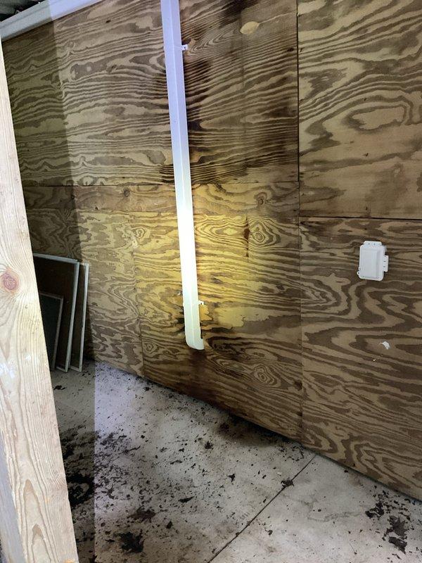 # Plumbing Leak Repair - Broken Pipe

Responded to a plumbing leak emergency in a 30-year-old residential property where a broken pipe was actively affecting one area of the home. Upon arrival, conducted a thorough inspection of the affected space, which revealed significant water damage and moisture infiltration in the plywood wall panels. The vertical PVC drainage pipe installation showed signs of failure, with visible water staining and discoloration patterns indicating sustained moisture exposure.

Assessed the extent of the damage, noting yellowish-brown water stains that had penetrated multiple wall panels in irregular patches. The concrete floor displayed scattered water marks and debris consistent with active leak conditions. Identified the source of the pipe failure and determined the necessary repair approach to restore proper function and prevent further water intrusion.

Performed the broken pipe repair, addressing the compromised section of the plumbing system. Ensured all