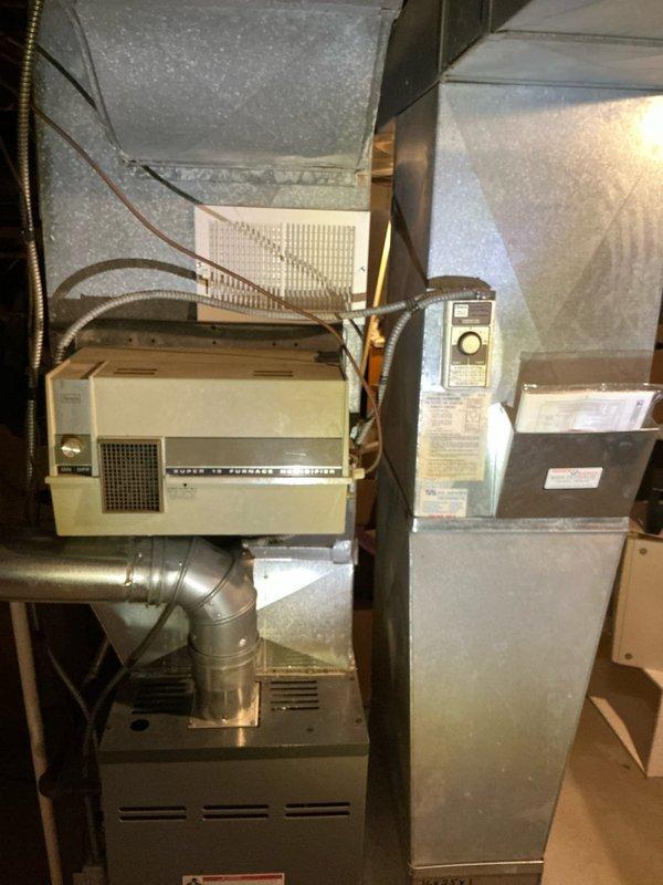 Conducted comprehensive furnace replacement estimate for residential property with existing aging HVAC system in basement utility space. Evaluated current furnace unit showing signs of wear and documented complete system layout including interconnected dehumidifier, air handler components, ductwork configuration, and PVC condensate drainage. Photographed equipment specifications, spatial constraints, and existing installation to provide accurate replacement recommendations and system upgrade options.