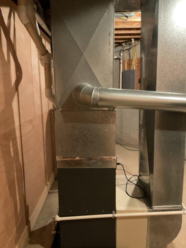 Responded to service call for air conditioning system not cooling with suspected refrigerant leak. Upon arrival, inspected 22-year-old Carrier air handler unit and associated HVAC equipment located in basement utility area. Visual assessment revealed aging system with significant rust and weathering on furnace casing, copper refrigerant lines, and connected ductwork. Documented existing equipment configuration including air handler, furnace unit, PVC condensate drainage, electrical connections, and refrigerant line routing for estimate preparation. Photographed installation to support diagnostic findings and provide visual reference for recommended repairs or replacement options.