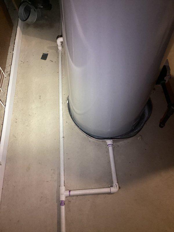 Responded to service call for non-heating water heater and sump pump spraying water onto basement floor. Upon inspection, found 4-year-old water heater with no hot water production and active sump pump discharge issue causing water spillage. Assessed water heater components, PVC discharge piping configuration, and sump pump basin assembly. Documented equipment conditions including water heater tank, copper and PVC supply lines, pump mechanism submerged in basin, and concrete floor water damage from sump discharge malfunction.