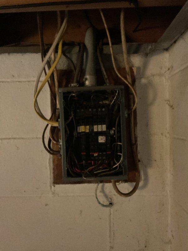 Completed electrical estimate for installation of replacement panel door on existing residential electrical service panel. Assessed older-style main distribution panel with exposed interior components, circuit breakers, and bus bars located in basement utility area. Evaluated exterior service entrance equipment including weatherhead, meter base, and conduit system on exterior wall to ensure compatibility with interior panel specifications for proper door replacement and code compliance.
