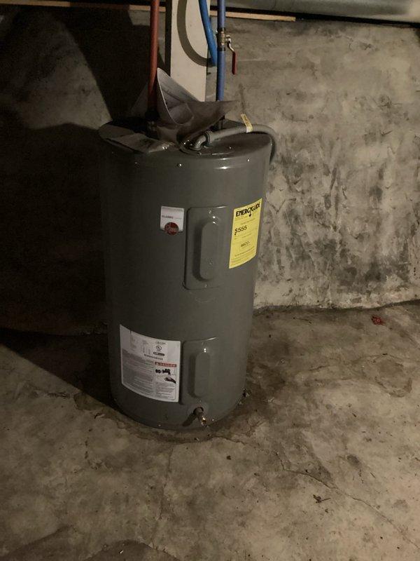 Performed inspector correction to verify water heater venting configuration in multi-unit property. Accessed lower unit to identify water heater type and document venting system to confirm no dual water heater venting into single chimney. Photographed lower unit water heater installation showing gas-fired unit with copper supply lines and pressure relief piping in basement utility area. Re-inspected upper floor water heater venting to verify proper chimney liner installation and code compliance.