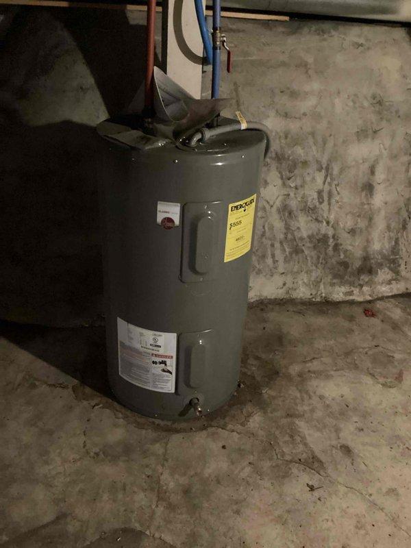 Performed inspector correction to verify water heater venting configuration in multi-unit property. Accessed lower unit to identify water heater type and document venting system to confirm no dual water heater venting into single chimney. Photographed lower unit water heater installation showing gas-fired unit with copper supply lines and pressure relief piping in basement utility area. Re-inspected upper floor water heater venting to verify proper chimney liner installation and code compliance.