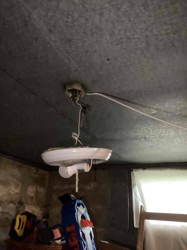 Completed comprehensive electrical safety inspection of 88-year-old residential property to assess wiring condition and identify potential hazards. Inspection revealed significant concerns including improperly installed light fixture with exposed wiring hanging loosely from ceiling mount, evidence of severe moisture damage and possible mold growth on ceiling materials near electrical components, and deteriorated wall conditions exposing underlying materials in multiple areas. Additionally observed non-standard plumbing installation with sink suspended from ceiling joists in basement utility area, raising concerns about potential water intrusion affecting nearby electrical systems. Documented all findings with photographs for homeowner review and provided recommendations for immediate remediation of exposed wiring hazards and professional assessment of moisture damage before proceeding with any electrical repairs.