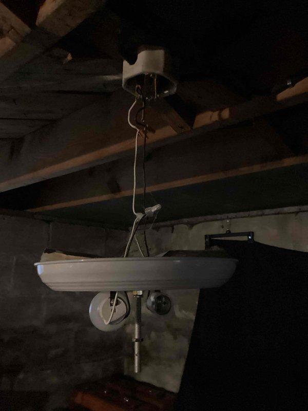 Completed comprehensive electrical safety inspection of 88-year-old residential property to assess wiring condition and identify potential hazards. Inspection revealed significant concerns including improperly installed light fixture with exposed wiring hanging loosely from ceiling mount, evidence of severe moisture damage and possible mold growth on ceiling materials near electrical components, and deteriorated wall conditions exposing underlying materials in multiple areas. Additionally observed non-standard plumbing installation with sink suspended from ceiling joists in basement utility area, raising concerns about potential water intrusion affecting nearby electrical systems. Documented all findings with photographs for homeowner review and provided recommendations for immediate remediation of exposed wiring hazards and professional assessment of moisture damage before proceeding with any electrical repairs.