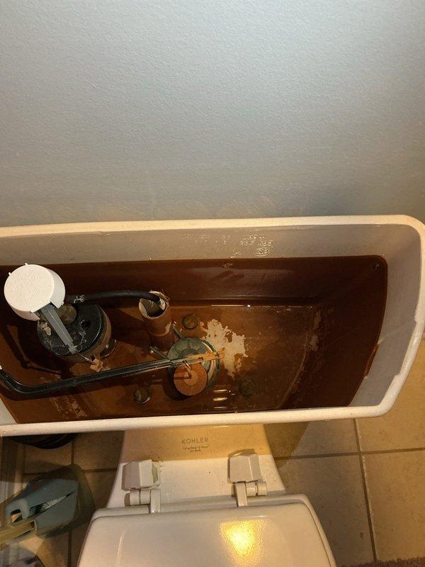 Responded to service call for leaking toilet with broken valve in home rebuilt around 2000. Upon inspection, removed tank lid and identified severely corroded fill valve assembly with compromised internal components, evidenced by brown discolored water indicating significant rust and mineral buildup throughout tank. Replaced faulty fill valve assembly with new unit, flushed system multiple times to clear sediment, and tested for proper operation and leak elimination. Verified no water leakage after restoration of water supply and confirmed all tank components functioning correctly.