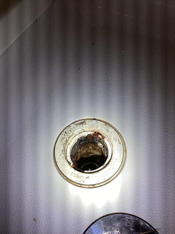 Responded to odor complaint in basement bathroom and sump pump room. Upon inspection, discovered corroded and stained sump pump basin with significant rust buildup around the discharge opening, indicating potential standing water and bacterial growth contributing to foul odors. Examined bathroom sink drain assembly and confirmed P-trap was properly installed and maintaining water seal. Documented conditions with photographs showing extent of corrosion in sump system and verified proper drainage configuration under sink to rule out dry trap as odor source.