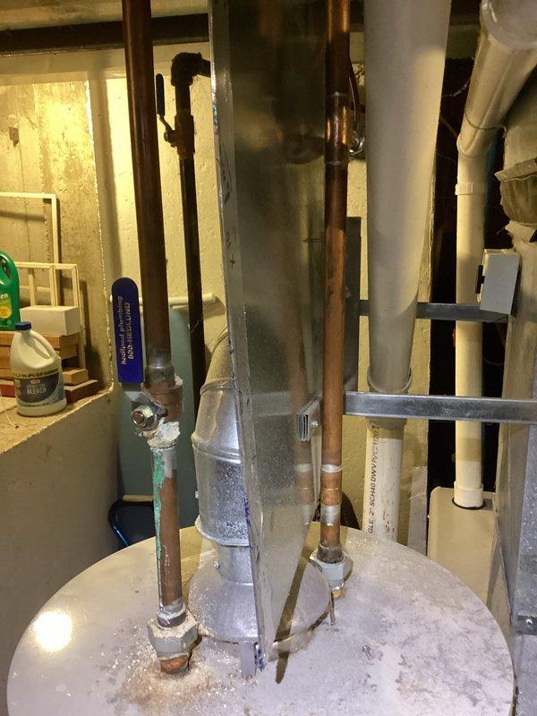 Responded to no hot water complaint on 27-year-old Bradford White water heater. Upon inspection, found unit had reached end of serviceable life with significant mineral deposit accumulation on top of tank and aging copper supply lines showing patina. Documented equipment condition with photos showing extensive frost/mineral buildup on tank top and overall plumbing configuration in mechanical room. Advised customer of water heater age and condition requiring replacement.