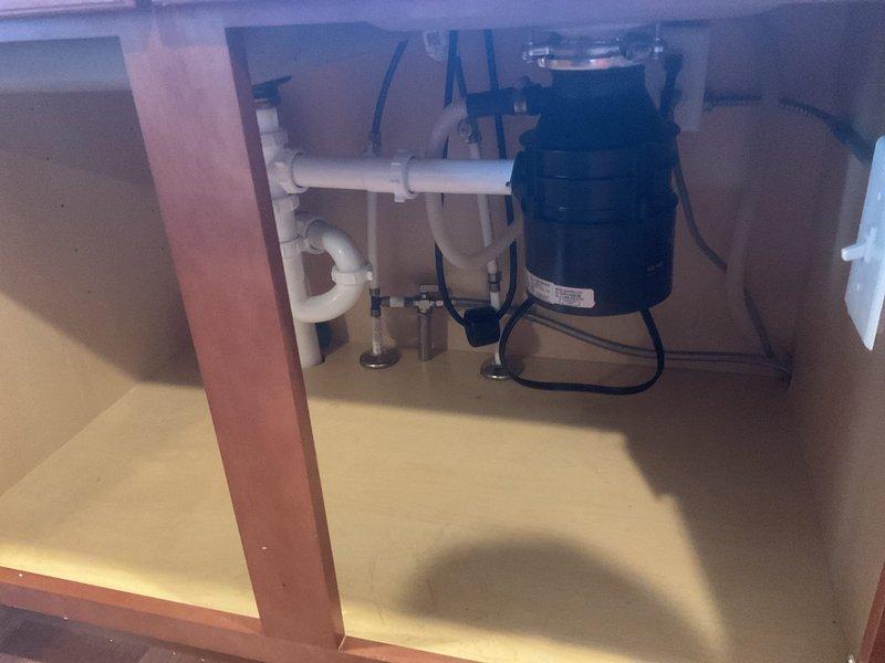 Installed new garbage disposal unit beneath kitchen sink with proper electrical connections and integrated PVC drain plumbing including P-trap configuration. All components tested and verified operational upon completion.