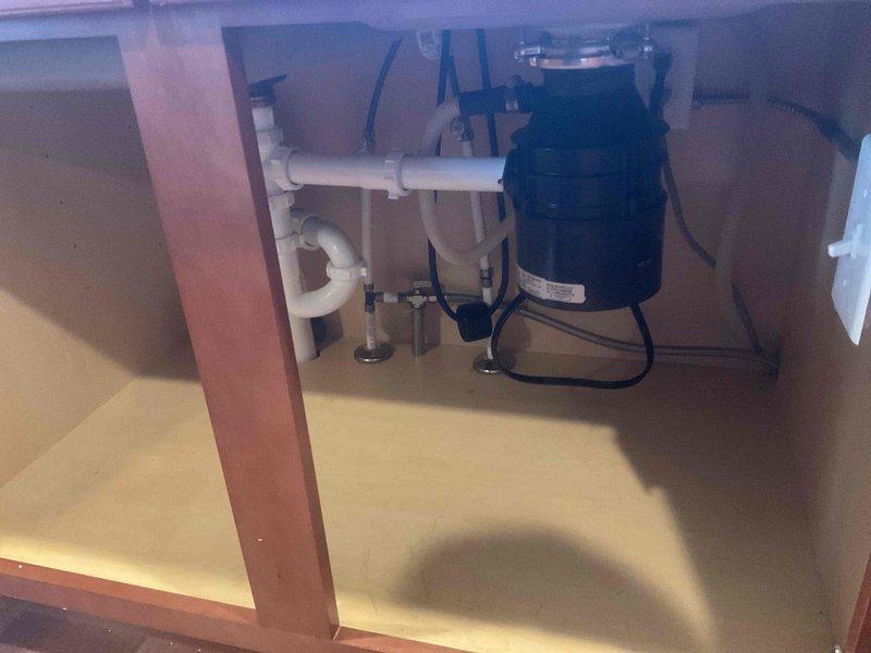 Installed new garbage disposal unit beneath kitchen sink with proper electrical connections and integrated PVC drain plumbing including P-trap configuration. All components tested and verified operational upon completion.