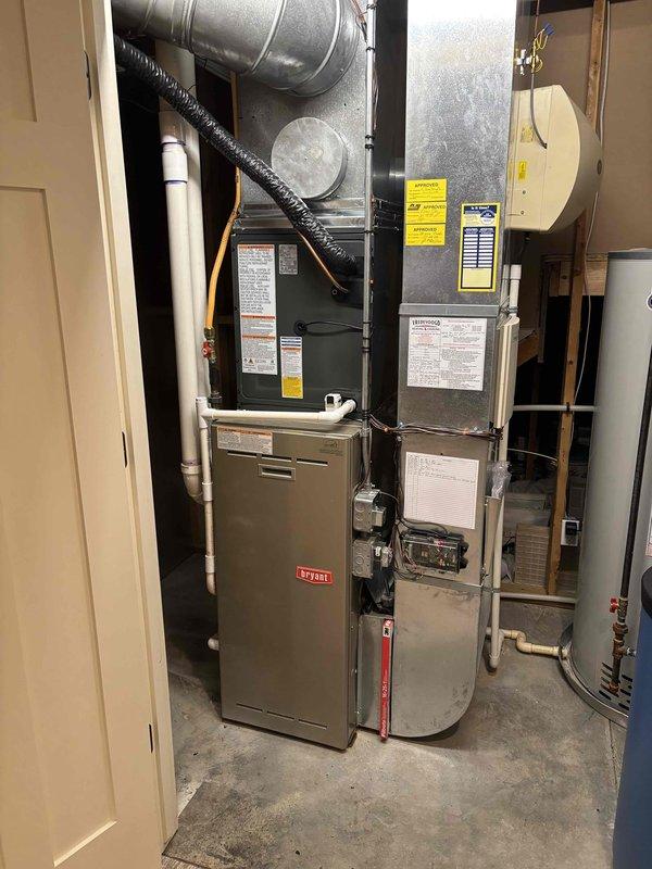Completed full air conditioning system replacement at residential property. Installed new outdoor condenser unit on existing concrete pad with proper electrical disconnect and conduit routing through decorative stone bed, ensuring adequate clearance from structure. Interior installation included new air handler unit positioned adjacent to existing Bryant furnace in mechanical room, with all refrigerant lines, condensate drainage, and ductwork connections properly completed and tested for optimal system performance.