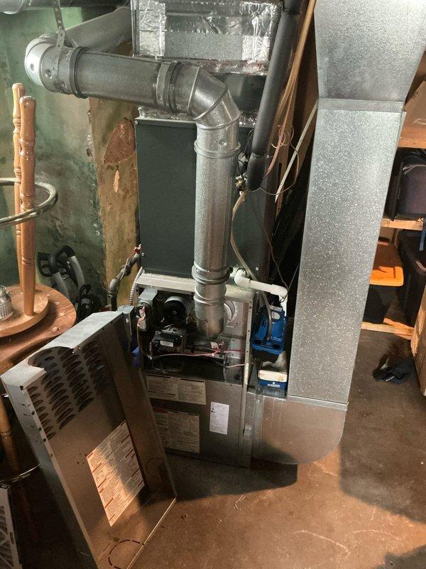 Conducted on-site assessment of non-operational furnace system in basement mechanical room. Documented existing HVAC equipment configuration including furnace unit, metal ductwork, exhaust venting with 90-degree elbow joint, and associated air handling components. Photographed current installation showing galvanized steel exhaust piping, aluminum foil-wrapped ductwork connections, copper supply lines, and insulated plenum assembly to provide comprehensive estimate for furnace replacement or repair.