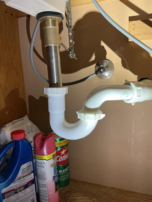 Completed QUOTR-quoted repair involving replacement of a faulty 1-inch pressure vacuum breaker on exterior irrigation system and installation of new bathroom sink pop-up assembly. The exterior pressure vacuum breaker was removed from the wall-mounted plumbing configuration and replaced with a new brass backflow prevention device, ensuring proper protection against contamination of the potable water supply. Inside, the bathroom sink drain assembly was serviced by installing a new pop-up mechanism with chrome finish, including drain body, pivot rod, and lift rod components, all properly sealed and connected to the existing white PVC P-trap. Both repairs restore full functionality to the plumbing fixtures and maintain code compliance for backflow prevention.