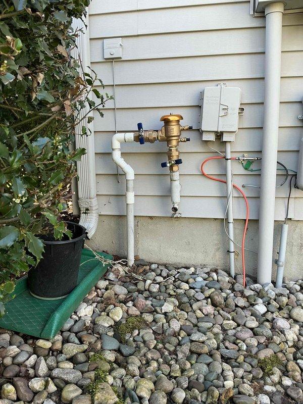 Completed QUOTR-quoted repair involving replacement of a faulty 1-inch pressure vacuum breaker on exterior irrigation system and installation of new bathroom sink pop-up assembly. The exterior pressure vacuum breaker was removed from the wall-mounted plumbing configuration and replaced with a new brass backflow prevention device, ensuring proper protection against contamination of the potable water supply. Inside, the bathroom sink drain assembly was serviced by installing a new pop-up mechanism with chrome finish, including drain body, pivot rod, and lift rod components, all properly sealed and connected to the existing white PVC P-trap. Both repairs restore full functionality to the plumbing fixtures and maintain code compliance for backflow prevention.