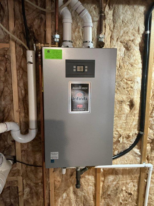 Responded to service call for Bradford White water heater reported as not heating consistently. Upon arrival, found unit to be an Infiniti tankless water heater approximately 5 years old, not the tank-type Bradford White initially reported. Inspected unit displaying temperature reading of 82°F on digital control panel. Evaluated all plumbing connections, venting system including white PVC exhaust pipes, copper water lines, and electrical connections for proper operation. Documented installation with photos showing complete system setup including ductwork and HVAC components in utility area. System assessed and customer advised of findings regarding inconsistent heating performance.