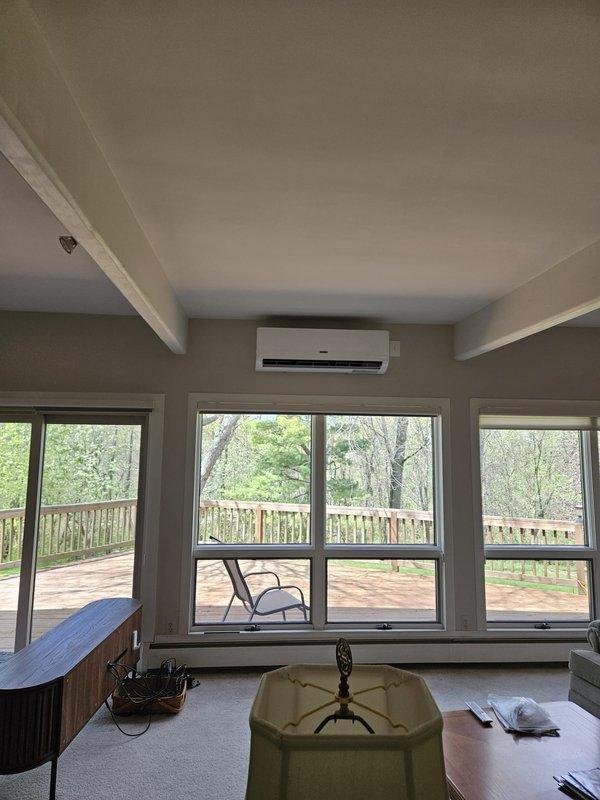 Completed installation of ductless mini-split system in residential sunroom with covered porch area. Mounted indoor air handler unit on interior wall above window bank, established refrigerant line connections to outdoor condenser unit, and ran electrical supply and control wiring through exterior wall penetrations. System tested and verified operational with proper cooling capacity and airflow distribution throughout the space.
