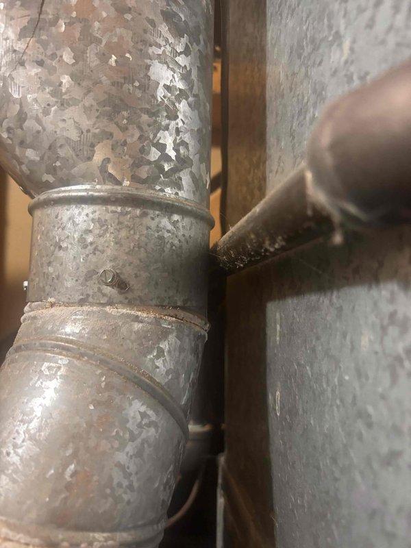 Completed annual AC tune-up and cooling system inspection on a 2019 Carrier unit as part of recurring maintenance program. Performed comprehensive system evaluation including refrigerant levels, electrical connections, and airflow verification. Inspected ductwork components in mechanical space, noting aged metal ductwork with surface deterioration and paint degradation consistent with system age. Observed active condensation on supply ductwork and piping, indicating proper cooling operation and humidity conditions. All system components operating within normal parameters with no immediate service needs identified.