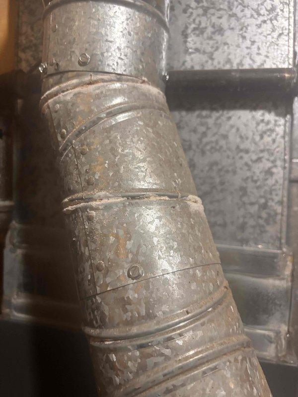Completed annual AC tune-up and cooling system inspection on a 2019 Carrier unit as part of recurring maintenance program. Performed comprehensive system evaluation including refrigerant levels, electrical connections, and airflow verification. Inspected ductwork components in mechanical space, noting aged metal ductwork with surface deterioration and paint degradation consistent with system age. Observed active condensation on supply ductwork and piping, indicating proper cooling operation and humidity conditions. All system components operating within normal parameters with no immediate service needs identified.