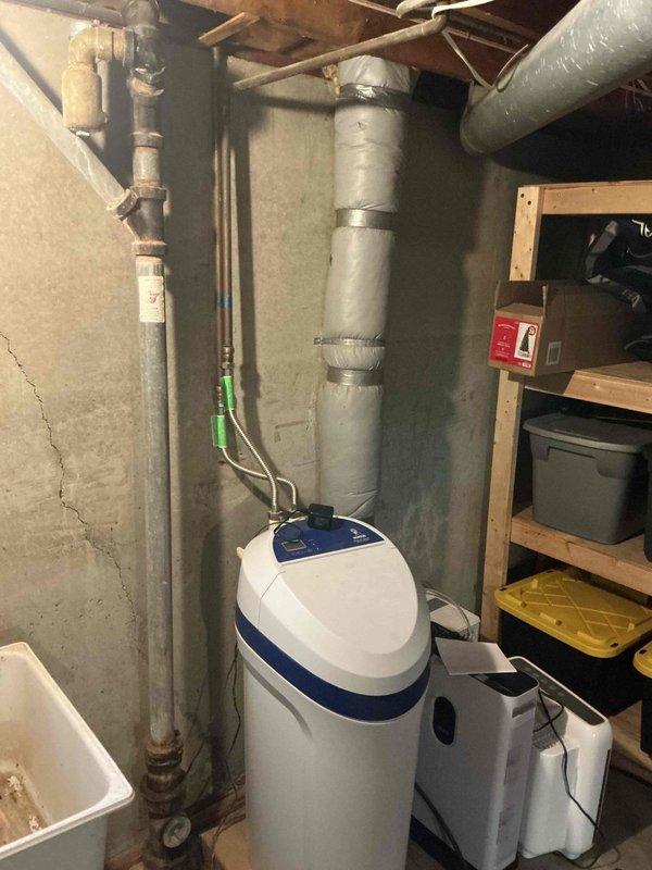 Responded to service call for inactive water softener that had been unplugged since property purchase. Upon arrival, located unit in basement utility area and performed complete system inspection. Verified all plumbing connections, including copper supply lines and PVC drain lines, were intact and properly secured. Checked brine tank salt levels and control valve operation. Restored power to unit, programmed control head with appropriate settings for household water usage, and initiated regeneration cycle to verify proper function. Tested water flow through softener and confirmed system returned to normal operation without leaks or operational issues.