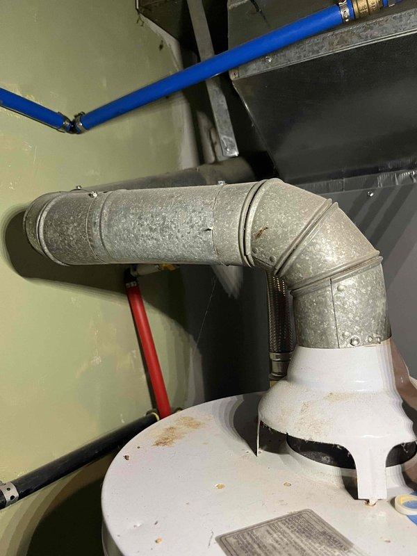 Responded to gas leak service call for 2011 ICP furnace emitting rotten egg odor during operation. Upon inspection, identified deteriorated and heat-damaged vent connector at wall penetration showing significant discoloration and oxidation. Conducted thorough safety assessment of venting system including flexible duct connections and galvanized ductwork. Documented condition of exhaust system components with visible signs of thermal stress and age-related degradation at mounting flange. System currently operational but venting components require replacement to ensure safe operation and proper combustion gas evacuation.