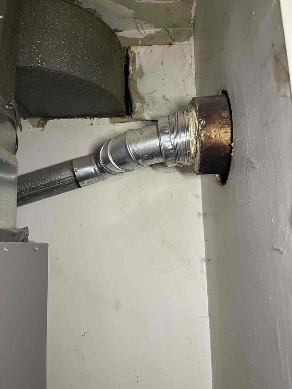 Responded to gas leak service call for 2011 ICP furnace emitting rotten egg odor during operation. Upon inspection, identified deteriorated and heat-damaged vent connector at wall penetration showing significant discoloration and oxidation. Conducted thorough safety assessment of venting system including flexible duct connections and galvanized ductwork. Documented condition of exhaust system components with visible signs of thermal stress and age-related degradation at mounting flange. System currently operational but venting components require replacement to ensure safe operation and proper combustion gas evacuation.