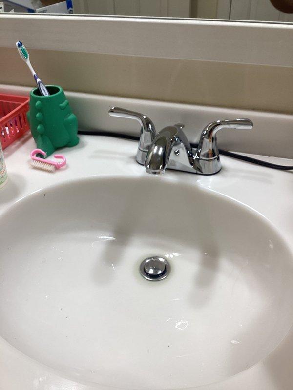 Completed faucet repair in residential bathroom, addressing water supply connection issues. Serviced two-handle chrome faucet assembly, secured water supply lines with proper connections, and verified all plumbing components including P-trap and angle stop valves were functioning correctly. System tested and confirmed operational with no leaks detected.