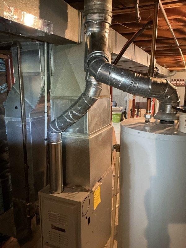 Completed HVAC venting repair work in basement utility area involving furnace ductwork system. Addressed severely corroded chimney cap and vent component showing extensive rust deterioration and paint failure on exterior rooftop installation.