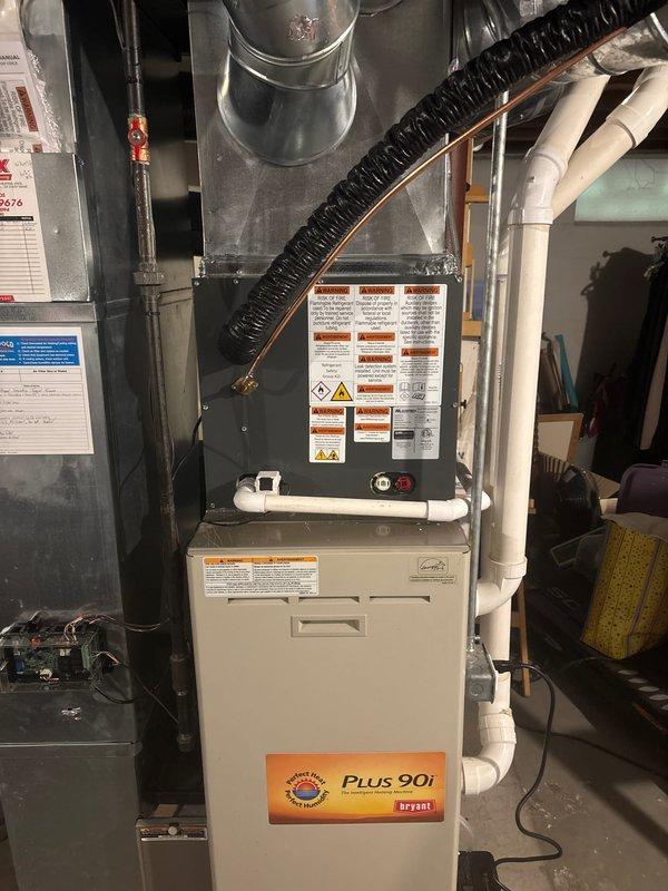 Completed full HVAC system replacement including outdoor condensing unit and indoor furnace components. Installed new Bryant PLUS 90i high-efficiency furnace in basement utility area with proper venting via white PVC piping and condensate drainage system. Mounted new outdoor air conditioning condenser unit on concrete pad adjacent to building exterior with proper clearances from gas meter and siding. Verified all electrical connections, refrigerant lines, and ductwork integration with existing metallic supply ducts. System tested and operational upon completion.