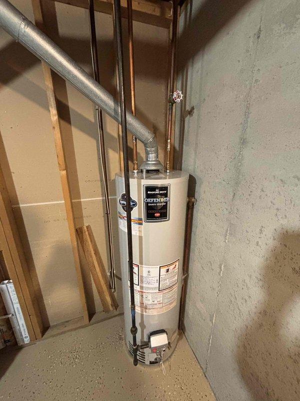 Conducted on-site assessment of existing Bradford White Defender water heater installation in residential basement utility room. Documented current equipment configuration including gas connections, copper supply lines, black iron gas piping, flue venting system, and surrounding mechanical infrastructure. Photographed water heater condition, pipe routing, electrical panel proximity, HVAC ductwork clearances, and overall installation environment to prepare comprehensive replacement estimate.