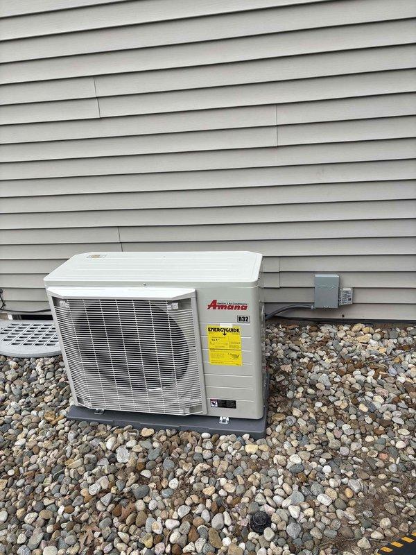 Completed full HVAC system installation including new furnace and Amana air conditioning condenser unit. Unit was properly mounted on composite pad with river rock landscaping base, electrical disconnect box installed per code, and all refrigerant lines and conduits secured to building exterior. System tested and operational upon completion.