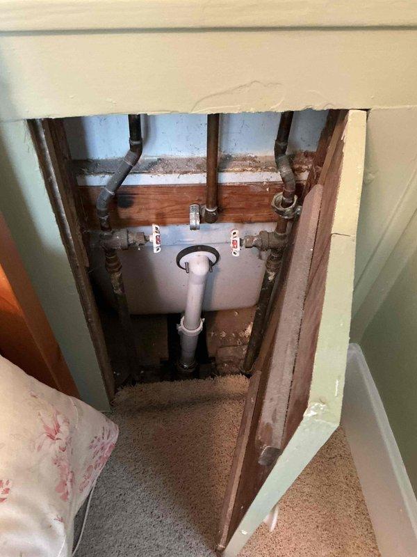 Responded to plumbing leak investigation request where drywall removal was performed by Camelot to access plumbing infrastructure. Located and documented water heater installation with associated shut-off valves and supply piping in wall cavity access point. Identified aged metal piping with visible oxidation and discoloration at pipe penetrations through framing, which appeared to be the source of moisture intrusion. Photographed plumbing configuration including red-handled isolation valves, supply lines, and PVC drainage connections for documentation and repair planning.