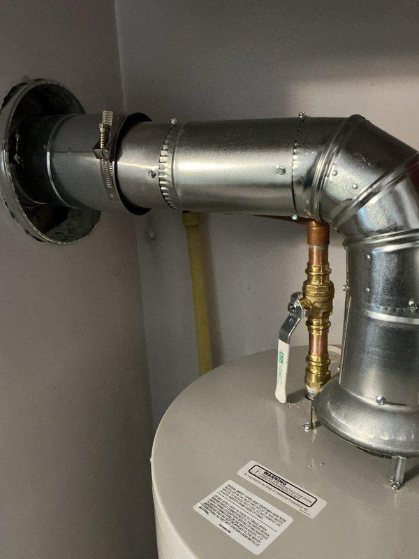 Completed installation of 40-gallon natural gas water heater with short configuration and chimney liner venting system in upper unit utility closet. Repositioned refrigerator to access installation area, installed new water heater with proper venting components including galvanized ductwork, elbow connections, and metal clamps to ensure code-compliant exhaust ventilation. All gas connections, pressure relief valve, and brass fittings were installed and tested for proper operation and safety compliance.