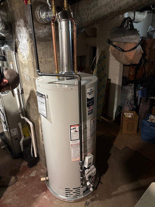 Completed full HVAC system installation including Carrier condensing unit positioned on concrete pad in side yard with proper clearances, new residential tank-style water heater installed in basement mechanical room with copper supply lines and expansion tank, and furnace installation as part of complete system replacement. All units connected per manufacturer specifications with appropriate electrical, gas, and plumbing connections, system tested and verified operational.