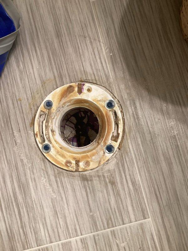 Responded to toilet stability issue in lower bathroom where fixture was loose on one side. Upon inspection, found deteriorated toilet flange with corrosion and wear on mounting hardware. Secured toilet by tightening existing bolts and replacing corroded fasteners with new hardware and washers to ensure proper seal and stability.