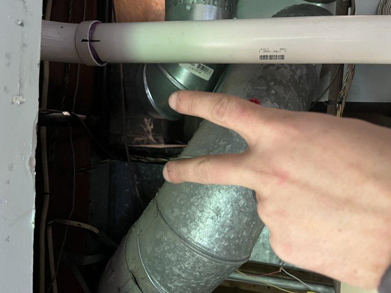 # No Heat Service Call - Goodman Furnace

Responded to no heat call for 18-year-old Goodman furnace blowing cold air only. Upon arrival, accessed unit in confined attic space and performed visual inspection of HVAC system components. Inspected ductwork connections, blower assembly, and associated mechanical components in cramped working conditions. Noted significant dust and debris accumulation on metallic duct elbows and connections throughout the system. Examined green blower motor assembly, flexible aluminum ductwork, and PVC condensate drainage piping. Photographed key system components for documentation purposes, including areas requiring attention due to dirt buildup on ductwork connections. System evaluated for proper airflow paths and mechanical integrity of installed components.