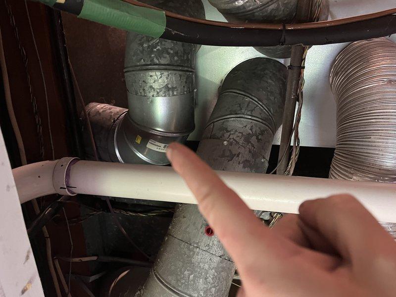 # No Heat Service Call - Goodman Furnace

Responded to no heat call for 18-year-old Goodman furnace blowing cold air only. Upon arrival, accessed unit in confined attic space and performed visual inspection of HVAC system components. Inspected ductwork connections, blower assembly, and associated mechanical components in cramped working conditions. Noted significant dust and debris accumulation on metallic duct elbows and connections throughout the system. Examined green blower motor assembly, flexible aluminum ductwork, and PVC condensate drainage piping. Photographed key system components for documentation purposes, including areas requiring attention due to dirt buildup on ductwork connections. System evaluated for proper airflow paths and mechanical integrity of installed components.
