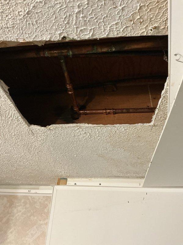 Responded to water leak discovered by electricians during their work. Created ceiling access opening to expose and assess copper plumbing lines showing age-related corrosion and patina buildup. Documented existing conditions with photos showing compromised piping in ceiling cavity above window area.