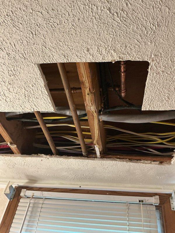 Responded to water leak discovered by electricians during their work. Created ceiling access opening to expose and assess copper plumbing lines showing age-related corrosion and patina buildup. Documented existing conditions with photos showing compromised piping in ceiling cavity above window area.