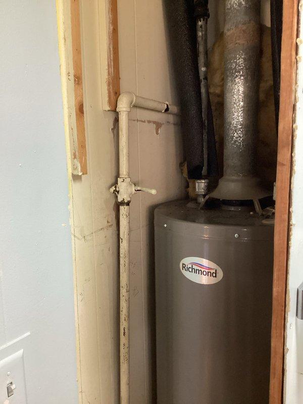 Responded to service call for water heater fitting issues at a commercial building with residential-style installation. Upon arrival, inspected Richmond brand tank-style water heater located in basement utility space. Evaluated existing plumbing connections including PVC supply lines, galvanized piping with visible condensation, and drainage connections. Assessed fitting conditions and water heater accessibility within framed wall cavity. Documented unit specifications and current installation configuration to determine serviceability and provide recommendations for necessary repairs to plumbing connections.
