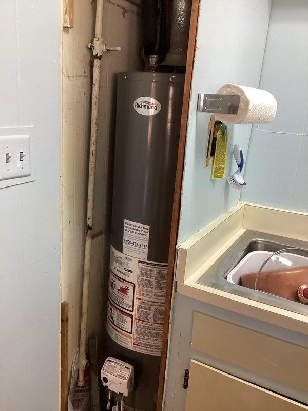 Responded to service call for water heater fitting issues at a commercial building with residential-style installation. Upon arrival, inspected Richmond brand tank-style water heater located in basement utility space. Evaluated existing plumbing connections including PVC supply lines, galvanized piping with visible condensation, and drainage connections. Assessed fitting conditions and water heater accessibility within framed wall cavity. Documented unit specifications and current installation configuration to determine serviceability and provide recommendations for necessary repairs to plumbing connections.