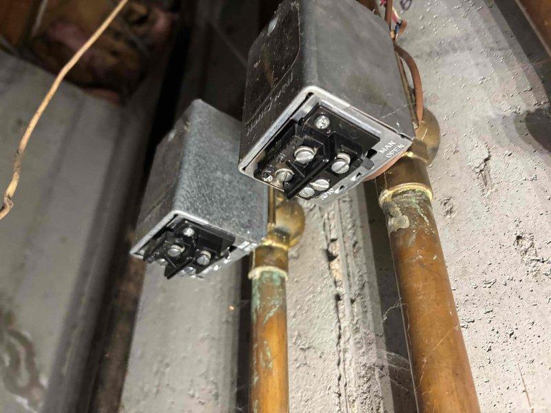 Responded to service call for boiler not reaching set temperature on 10-year-old system. Upon inspection, identified control unit malfunction preventing proper temperature regulation. Examined wall-mounted heating control with digital display and associated valve manifold system including multiple brass fittings with colored handles. Assessed copper piping connections and electrical junction boxes showing signs of age and patina buildup. Verified proper electrical connections at terminal points and evaluated overall system operation to restore heating functionality to programmed temperature settings.