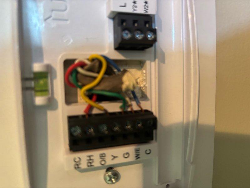 Responded to service call for home experiencing inconsistent heating and cooling performance requiring frequent thermostat adjustments. Upon inspection, found improperly configured thermostat wiring at the wall unit with multiple wire connections requiring verification at the terminal block. Removed thermostat cover to access RC, RH, Y, G, and C terminal connections and traced wiring back to the air handler control board. Inspected the main control board PCB with LED indicators and verified proper voltage at all connection terminals. Examined wire bundle routing between thermostat and HVAC system components, including connections to capacitors and refrigerant line assembly. Corrected thermostat wiring configuration to ensure proper communication between control systems. Verified all terminal connections were secure at both the wall unit and control board. Cycled system through heating and cooling modes to confirm proper operation and stable temperature control without requiring manual 