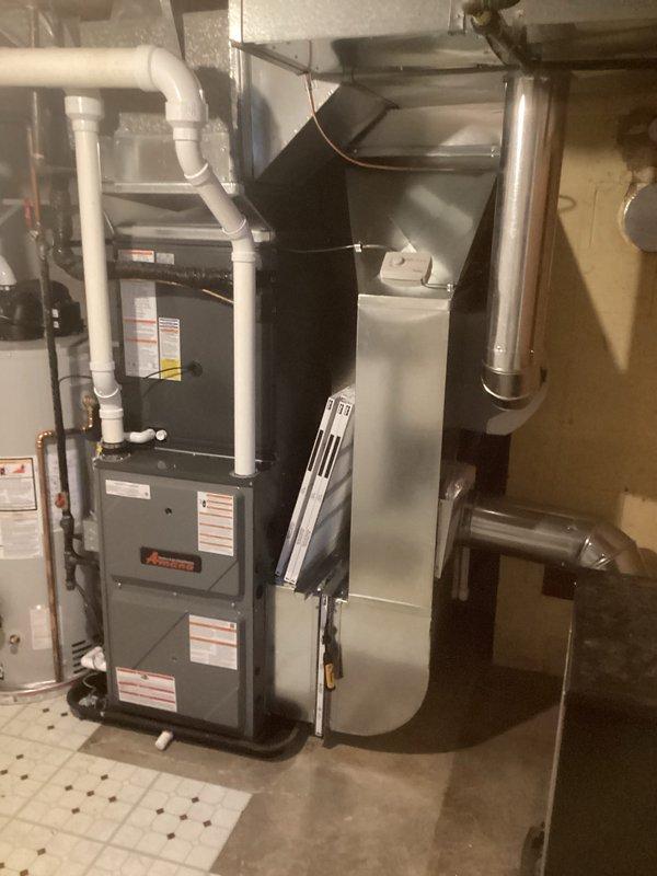 Completed full HVAC system installation in residential basement mechanical room, including new furnace unit with PVC condensate drain and venting lines, air conditioning system with metallic supply ductwork and vertical exhaust venting, and integrated piping infrastructure with copper and PVC components properly secured to floor joists with approved hangers and brackets.